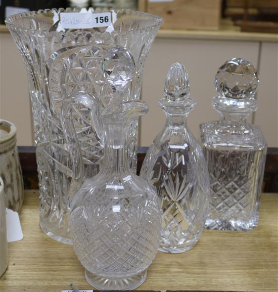A tall heavy cut glass vase, three decanters and a claret jug